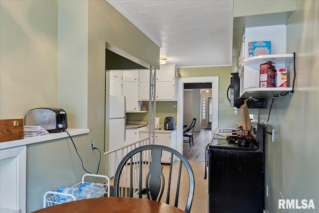 kitchen with hardwood / wood-style floors, white cabinets, a textured ceiling, and black appliances