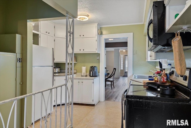 kitchen with white fridge, tasteful backsplash, range with electric stovetop, and white cabinetry