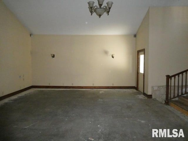 spare room featuring a notable chandelier, stairs, baseboards, and concrete flooring