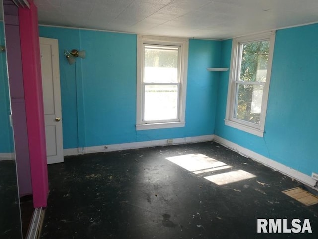 empty room featuring unfinished concrete floors and baseboards