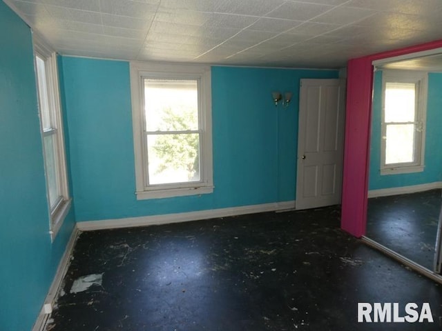 empty room featuring a healthy amount of sunlight, concrete floors, and baseboards