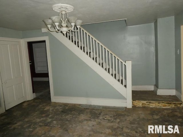 staircase featuring baseboards and a chandelier