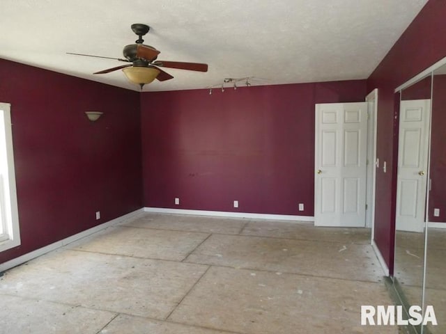 empty room with ceiling fan and baseboards