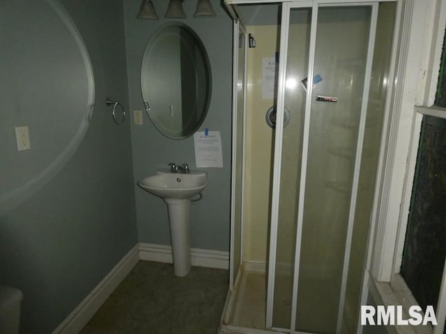 bathroom with a stall shower, baseboards, and a sink