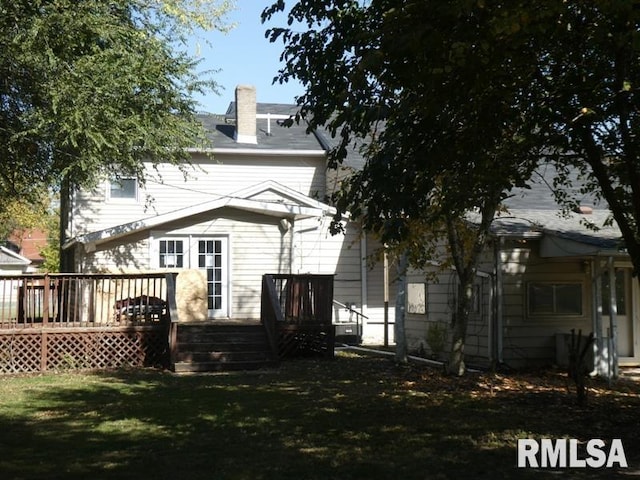 back of house with a chimney, a lawn, and a deck