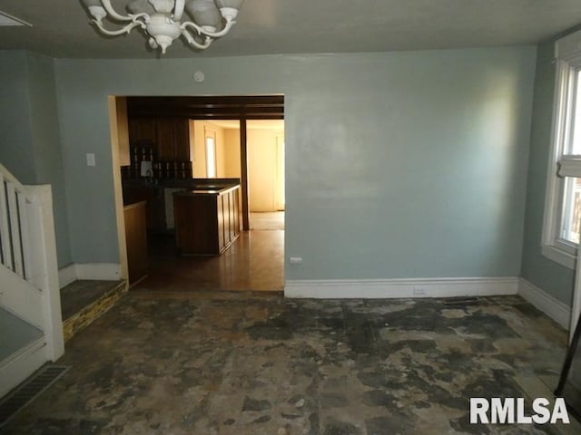 unfurnished dining area featuring baseboards and an inviting chandelier