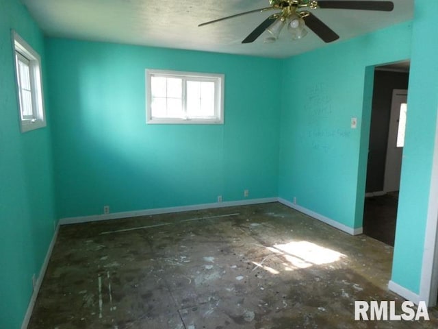 spare room featuring a ceiling fan, plenty of natural light, and baseboards