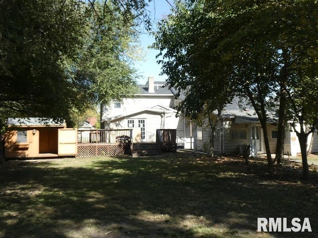 rear view of property with a storage unit, a deck, a lawn, and an outdoor structure