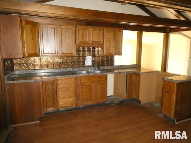 kitchen with dark countertops, decorative backsplash, brown cabinets, and dark wood-type flooring