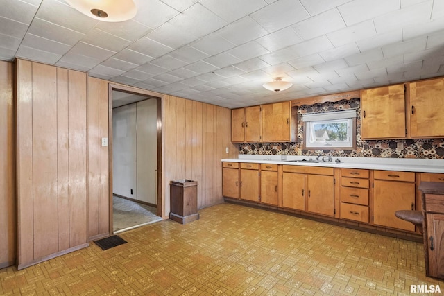 kitchen featuring tasteful backsplash, wooden walls, and sink