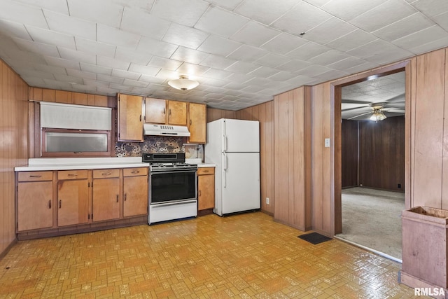 kitchen featuring wooden walls, tasteful backsplash, white appliances, and ceiling fan