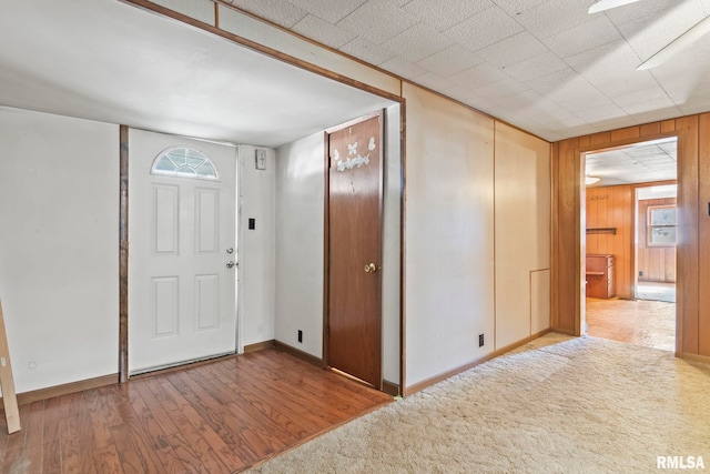 entryway with light hardwood / wood-style floors and wooden walls