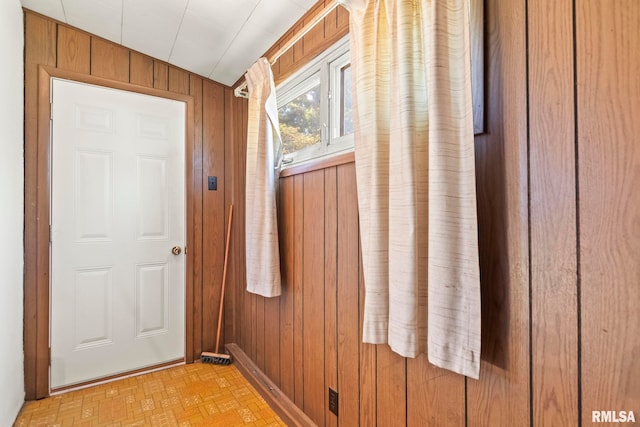 entryway featuring light parquet floors, wood walls, and lofted ceiling