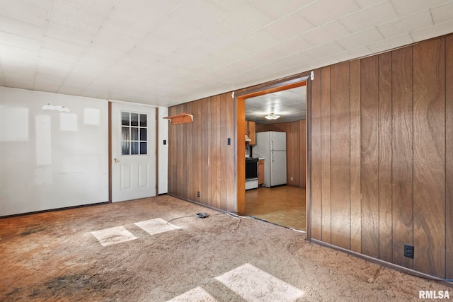 empty room featuring wooden walls and light carpet