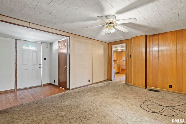 entrance foyer with wooden walls, hardwood / wood-style flooring, and ceiling fan