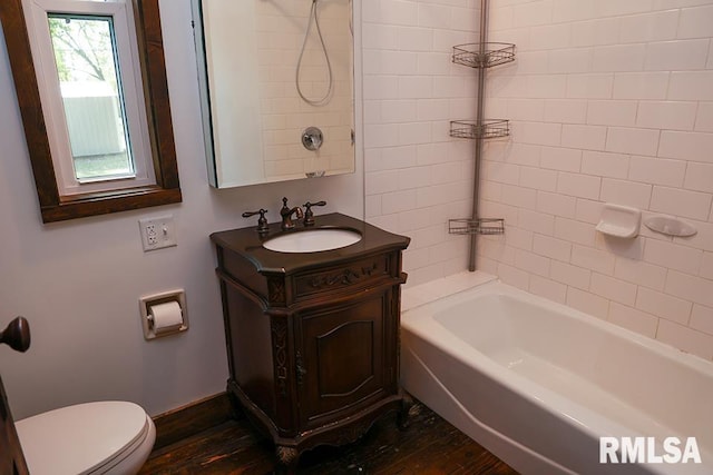 full bathroom with tiled shower / bath, vanity, hardwood / wood-style floors, and toilet