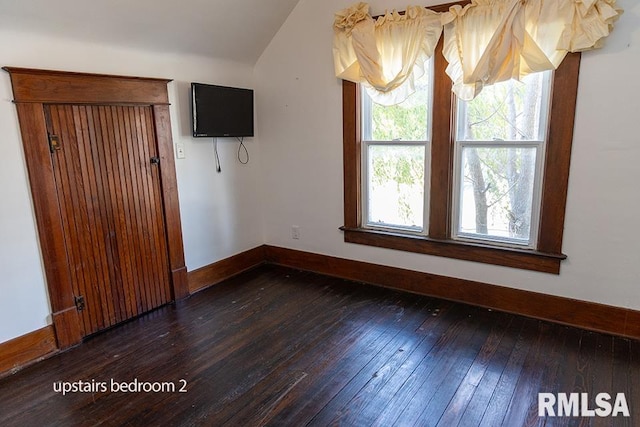 unfurnished room featuring dark wood-type flooring and vaulted ceiling