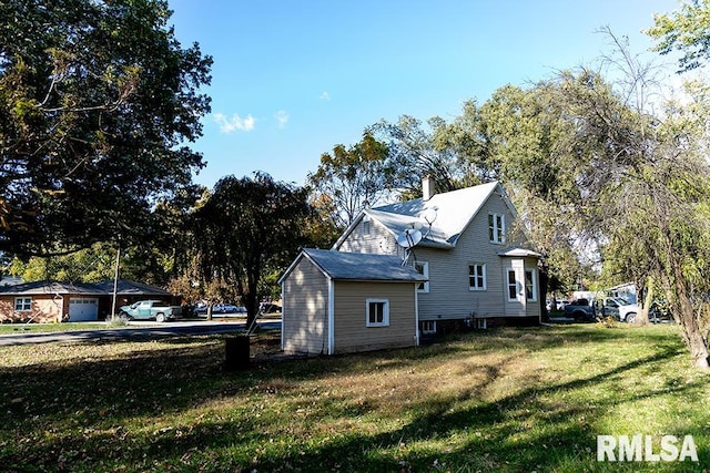 view of side of home featuring a yard, an outbuilding, and a garage