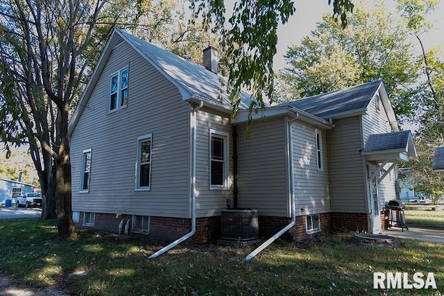 view of property exterior with cooling unit and a lawn