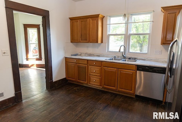 kitchen with tasteful backsplash, appliances with stainless steel finishes, sink, dark hardwood / wood-style flooring, and pendant lighting