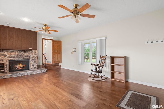 unfurnished living room featuring hardwood / wood-style floors, ceiling fan, a textured ceiling, and a stone fireplace