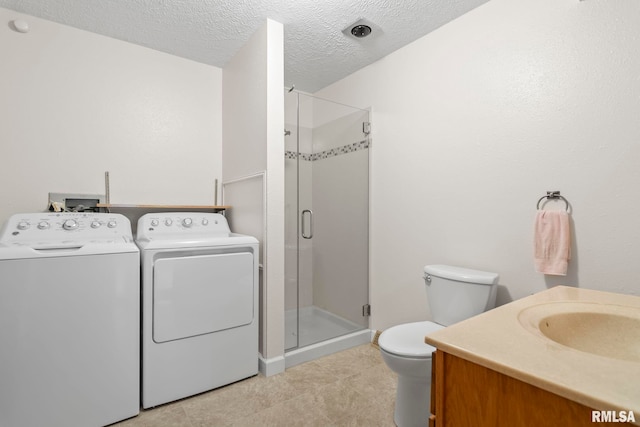 bathroom with vanity, a textured ceiling, toilet, washer and dryer, and a shower with shower door