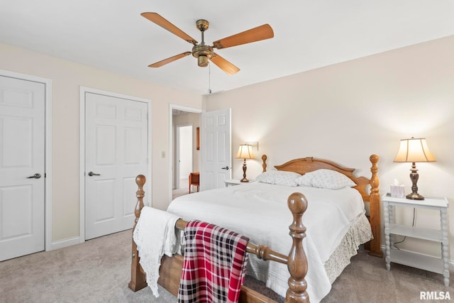 carpeted bedroom with ceiling fan and multiple closets