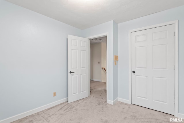 unfurnished bedroom featuring light colored carpet and a closet