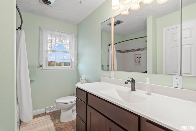 bathroom featuring vanity, tile patterned flooring, toilet, and a textured ceiling