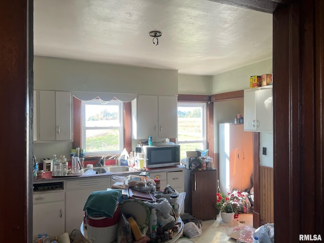 kitchen featuring dishwasher, sink, white cabinets, and a textured ceiling