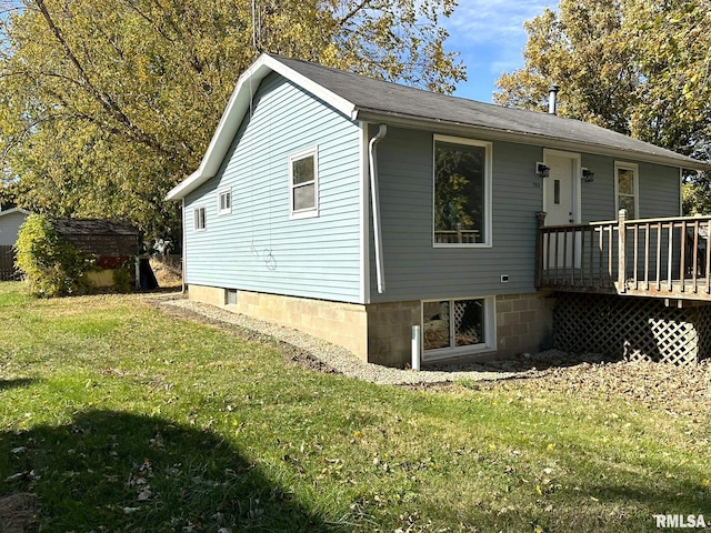 view of home's exterior with a wooden deck, a storage unit, and a lawn