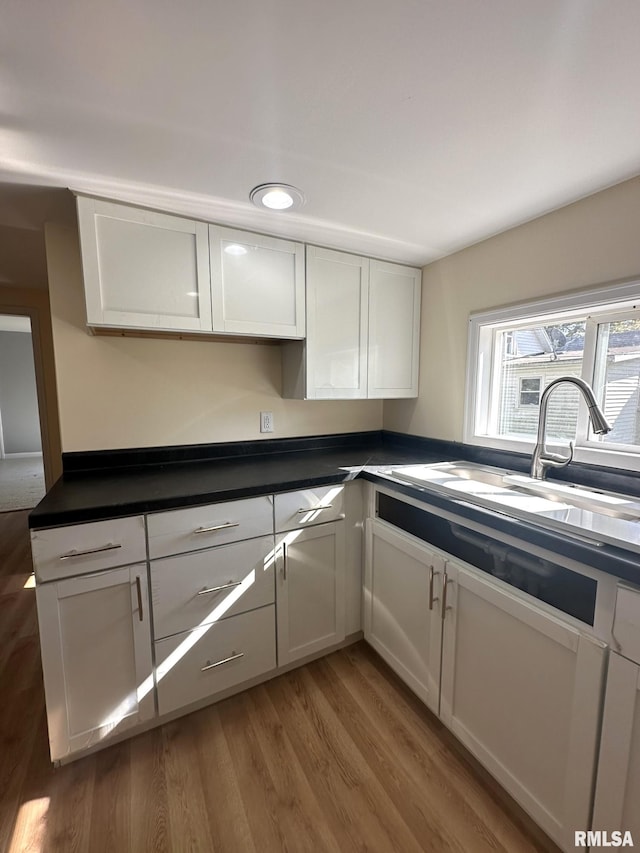 kitchen with white cabinetry, sink, and wood-type flooring