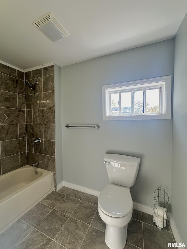 bathroom featuring a healthy amount of sunlight, tile patterned floors, tiled shower / bath, and toilet