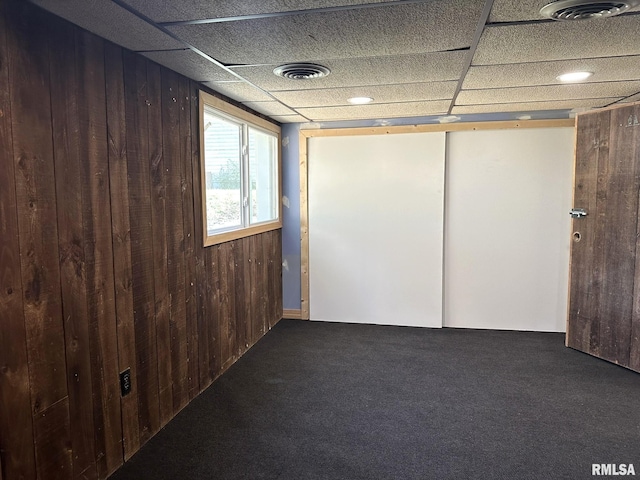 unfurnished room with carpet flooring and wood walls