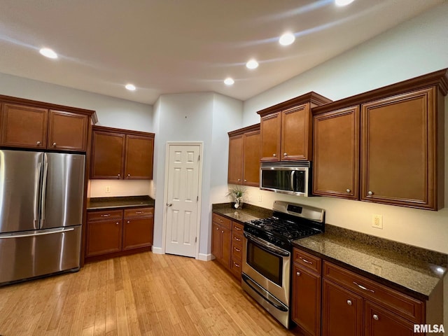 kitchen featuring light hardwood / wood-style flooring, stainless steel appliances, and dark stone counters