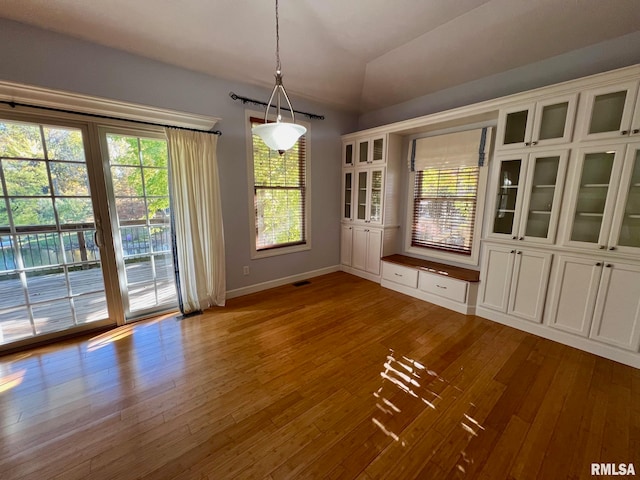 unfurnished dining area featuring hardwood / wood-style flooring, lofted ceiling, and a wealth of natural light