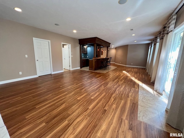 unfurnished living room featuring bar and dark hardwood / wood-style flooring