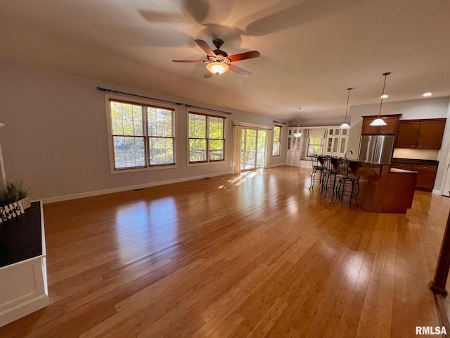 unfurnished living room with sink, ceiling fan, and light hardwood / wood-style flooring