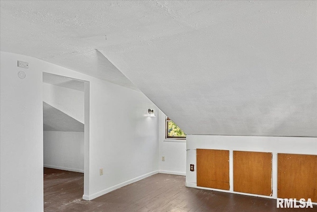 additional living space with lofted ceiling, dark hardwood / wood-style flooring, and a textured ceiling