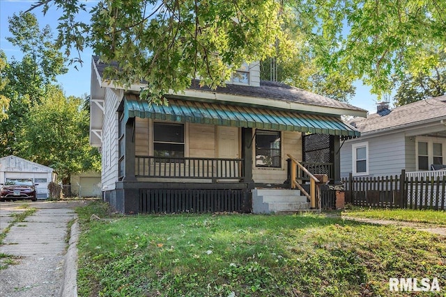 bungalow-style home featuring a garage, an outbuilding, a front yard, and covered porch