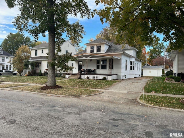 view of front of home featuring a front yard, a porch, an outbuilding, and a garage