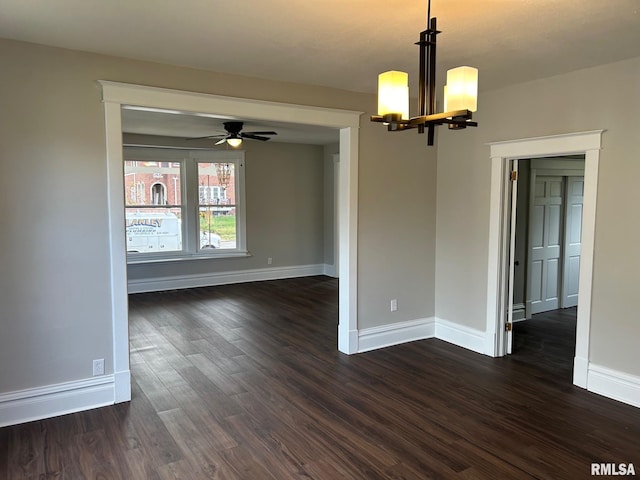 empty room with dark wood-type flooring and ceiling fan with notable chandelier