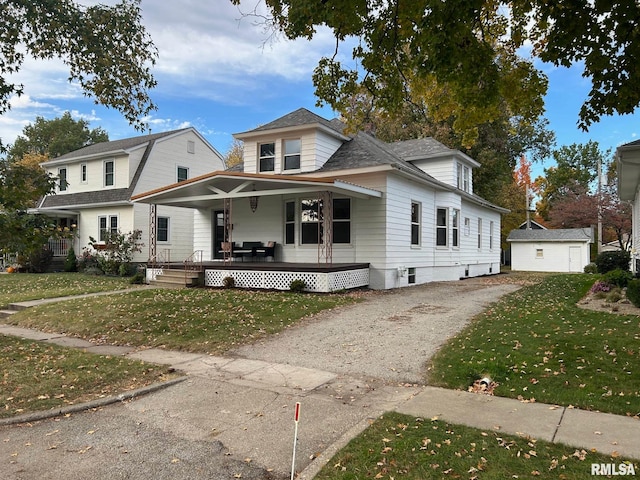 view of front of house featuring a front yard, an outdoor structure, a garage, and covered porch