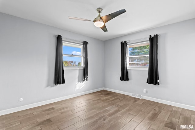 empty room with light hardwood / wood-style floors, ceiling fan, and a wealth of natural light