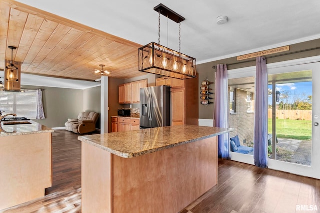 kitchen with dark wood-type flooring, a healthy amount of sunlight, decorative light fixtures, and stainless steel fridge