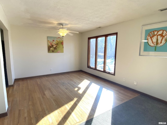 unfurnished room with ceiling fan, dark hardwood / wood-style flooring, and a textured ceiling