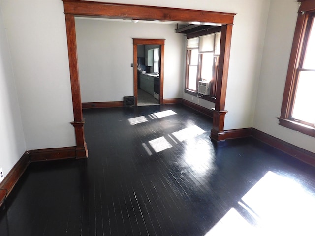 empty room featuring dark wood-type flooring, cooling unit, and plenty of natural light