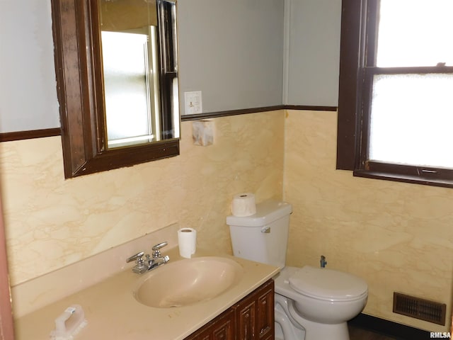 bathroom with vanity, toilet, and tile walls