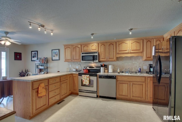 kitchen with sink, kitchen peninsula, stainless steel appliances, and a textured ceiling