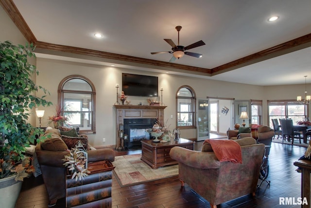 living room with ornamental molding, dark hardwood / wood-style floors, and ceiling fan with notable chandelier